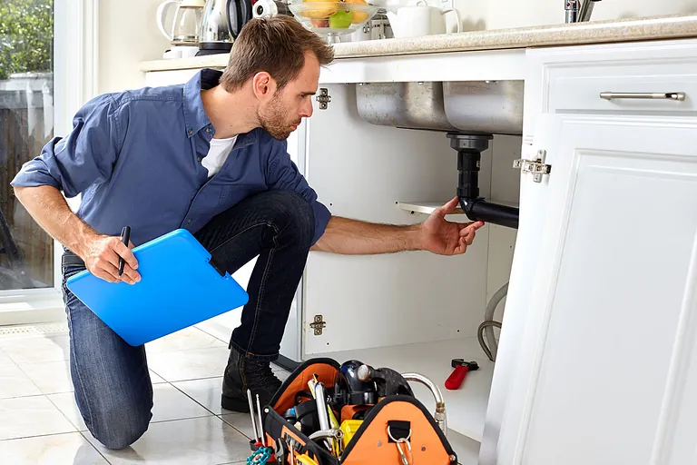 plumber checking under a kitchen sink